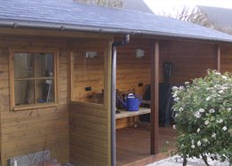 Houten veranda met overkapping naast een tuinhuis